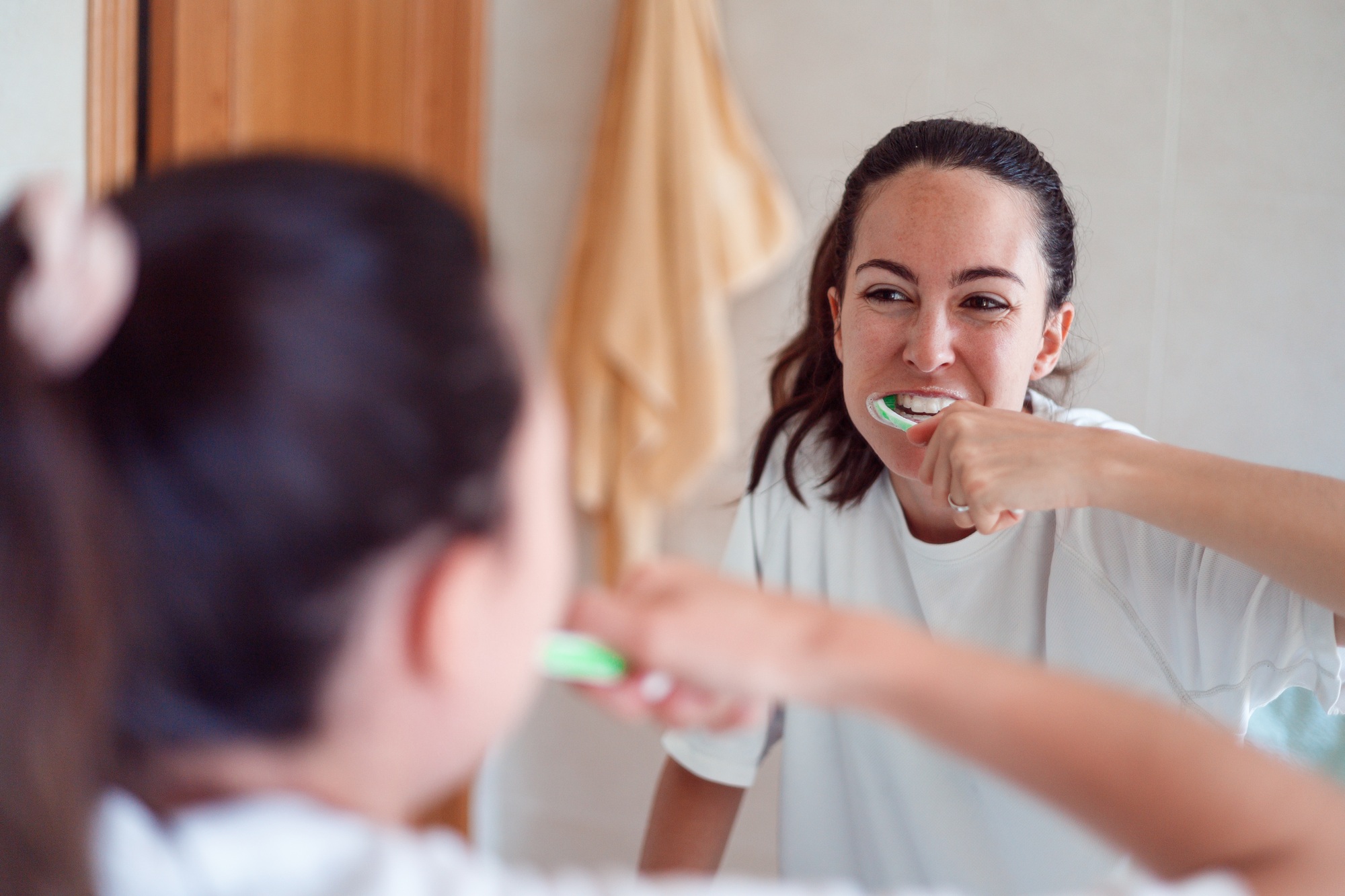 Smiling young woman brushing teeth in bathroom